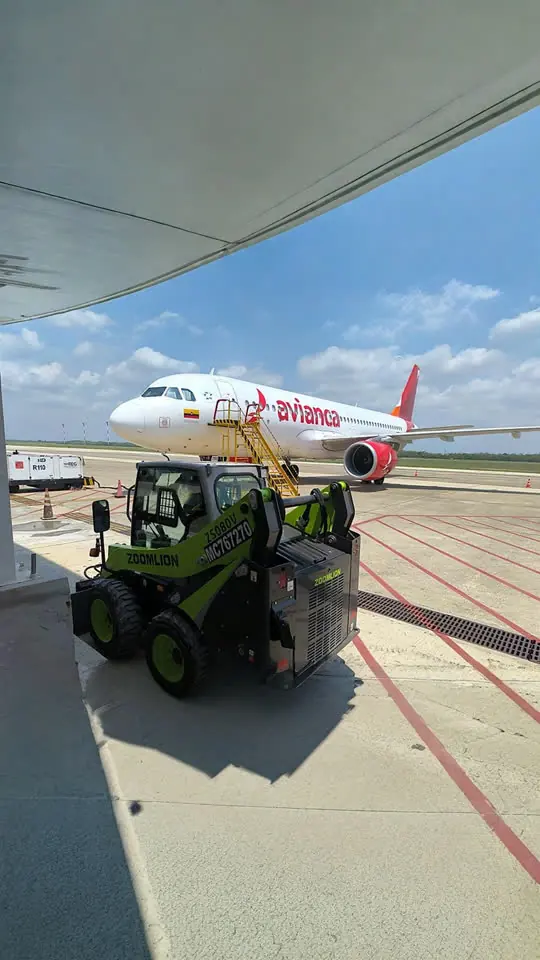 Minicargador Zoomlion junto a un avión en plataforma de aeropuerto